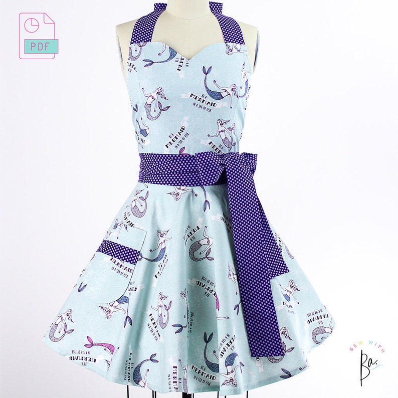 May include: A light blue apron with a mermaid print and the text "I'm a mermaid in a sea of fish". The apron has a purple polka dot tie.