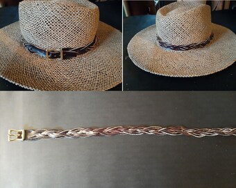 May include: A brown leather braided hat band with a brass buckle. The band is shown on a straw hat.