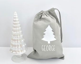 May include: A gray drawstring bag with a white Christmas tree design and the name "GEORGE" printed on the front.