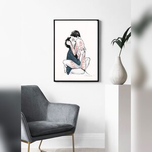May include: A framed art print featuring a black and white ink illustration of two figures embracing and kissing. One figure wears a dark shirt, while the other displays delicate red fern-like patterns across their skin. The artwork is signed.
