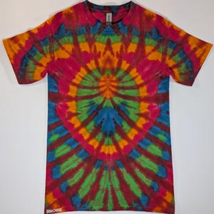 May include: A short-sleeved tie-dye t-shirt with a vibrant spiral pattern in shades of red, orange, yellow, green, and blue. The shirt has a crew neck and the text "DROCSOUD" is printed on the bottom left.