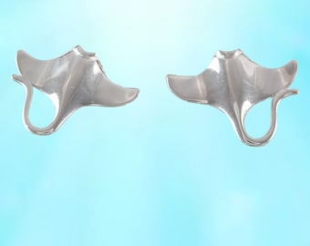 Könnte beinhalten: Ein Paar silberfarbene Ohrringe in Form von Mantarochen. Die Ohrringe sind zart und haben eine glatte, polierte Oberfläche.