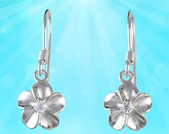 May include: A pair of silver dangle earrings featuring a flower design with a clear rhinestone in the centre.