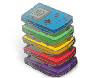 May include: A stack of seven enamel pins, each shaped like a retro handheld game console. The pins are layered in a rainbow pattern, starting with blue, green, yellow, orange, red, purple, and ending with a silver base.