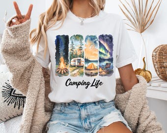May include: White t-shirt with a colorful camping-themed graphic. The design features four vertical panels depicting a campfire, a camper, a tent, and a starry night scene. The words "Camping Life" are printed below the panels.