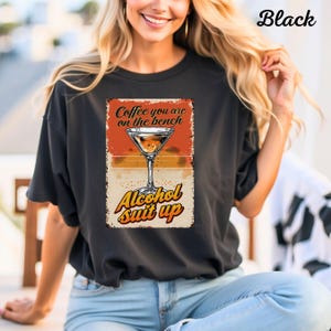 Puede incluir: Camiseta negra con un gráfico de estilo vintage que presenta una copa de martini y el texto "Coffee you are on the bench Alcohol suit up".