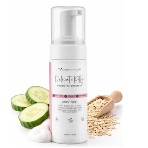 May include: A white cylindrical bottle of Delicate Kitty Probiotic Foam Wash with a clear pump dispenser. The label features pink accents, the text Mink Kitty Coat, and directions for use. Net weight 150 ml is printed on the front.