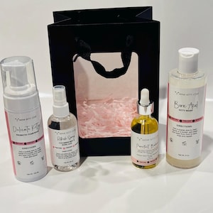 May include: A collection of Mink Kitty Coat products, including a probiotic foam wash, refresh spray, perfect balance oil, and boric acid kitty wash, arranged with a black gift bag. The products are in white bottles with pink and black labels.