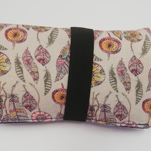 Op de afbeelding: Een rechthoekige, beige stoffen etui met een zwarte elastische bandsluiting. De etui is bedrukt met kleurrijke, gestileerde veren en cirkelvormige ontwerpen in tinten rood, geel en roze.