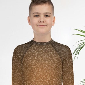 Op de afbeelding: Een bruin longsleeve shirt met een wit en bruin abstract patroon. Het shirt heeft een hoge hals en is gemaakt van een zacht, rekbaar materiaal.