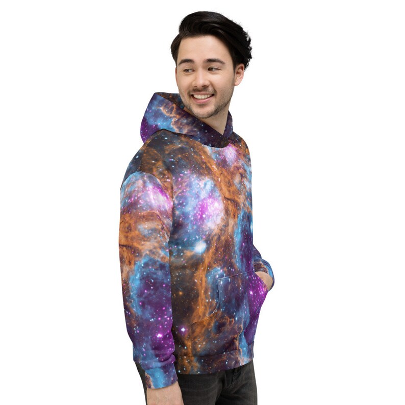 May include: A hooded sweatshirt featuring a vibrant galaxy design in shades of blue, purple, and orange. The pullover has a front pocket and a drawstring hood. The fabric appears soft and comfortable.
