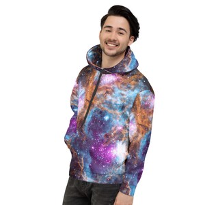 May include: A hooded sweatshirt featuring a vibrant galaxy print in shades of blue, purple, and orange. The hoodie has a drawstring and a front pocket. The overall design creates a cosmic and celestial theme.