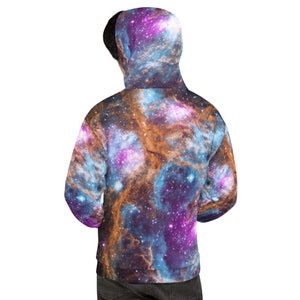 May include: A hooded sweatshirt featuring a vibrant galaxy design in shades of purple, blue, and orange. The back view of the sweatshirt shows the hood up, displaying the cosmic pattern. The fabric appears soft and comfortable.