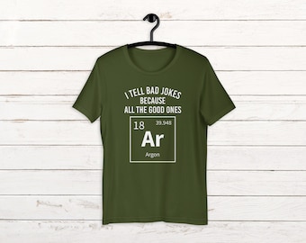 Op de afbeelding: Een groen T-shirt met de tekst "I tell bad jokes because all the good ones are Ar" met een periodiek systeem elementenbox voor Argon onder de tekst.