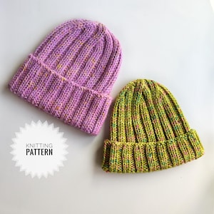 Może przedstawiać: Dwie dzianinowe czapki. Jedna jest jasnofioletowa z żółtymi i pomarańczowymi plamkami, a druga zielona z podobnymi plamkami. Obie mają prążkowany brzeg i teksturowany, pionowy wzór dzianiny. Widoczny jest tekst "KNITTING PATTERN".