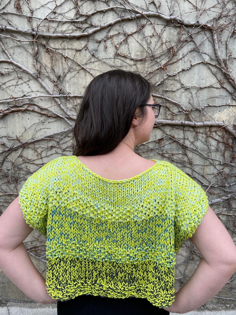 Puede incluir: Un top corto de punto de manga corta, de color amarillo, verde y negro, con un corte holgado.
