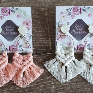 May include: Two pairs of handmade macrame earrings with a white opal bead and a silver hoop. One pair is pink and the other is white.