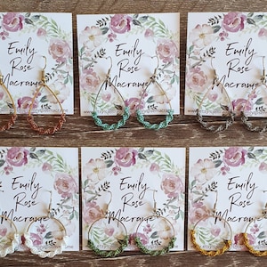 May include: Six pairs of handmade macrame earrings displayed on cards with the text "Emily Rose Macrame" and a website address. The earrings are in various colours, including brown, green, white, and yellow.