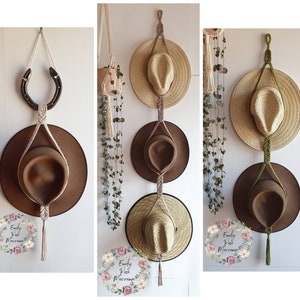 May include: Three macrame hat holders with different coloured cords and tassels. Each holder has three hats, one brown felt hat, one straw hat, and one brown felt hat. The holders are hung on a wall with a horseshoe hook.