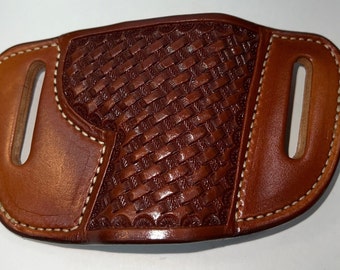 Könnte beinhalten: Ein braunes Lederholster mit einem gewebten Muster und weißen Nähten. Das Holster hat zwei Gürtelschlaufen.