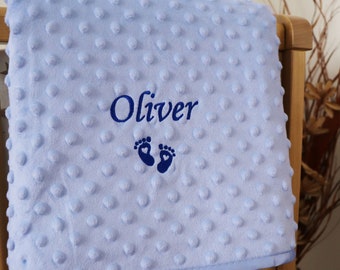 May include: A light blue baby blanket with a white border. The blanket is embroidered with the name "Oliver" and a pair of footprints with hearts.