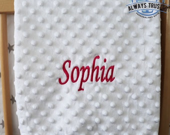 May include: White baby blanket with a textured surface and the name "Sophia" embroidered in red.