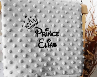 May include: A gray baby blanket with a black embroidered crown and the text "Prince Elias".