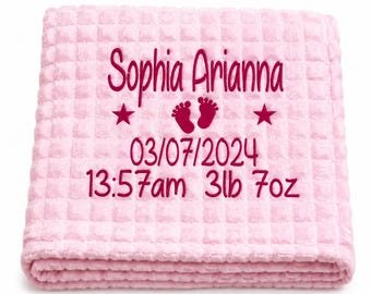 May include: A light pink waffle-textured blanket featuring dark pink embroidery. The text reads Sophia Arianna, 03/07/2024, 13:57am, and 3lb 7oz, accompanied by a pair of small footprints flanked by two five-pointed stars centered on the fabric.
