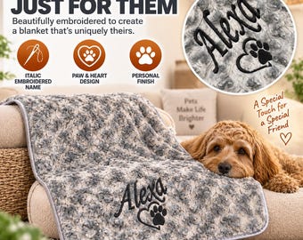 May include: A grey and white textured plush blanket featuring black embroidery of the name Alexa above a heart and paw print design. The blanket has a grey piped edge and is displayed with a golden-brown dog resting on it.