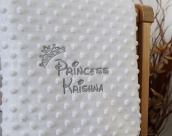 May include: White baby blanket with a gray embroidered crown and the text "Princess Krishna".