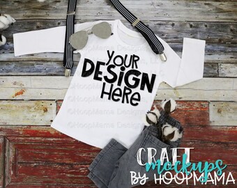 Puede incluir: Camiseta blanca de manga larga con el texto "YOUR DESIGN HERE" sobre un fondo de madera rústico. La camiseta está colocada plana con un par de tirantes y gafas de sol. Hay un pequeño grupo de bolas de algodón y un pantalón gris en la esquina inferior derecha. El texto "CRAFT MOCKUPS BY HOOPMAMA" está en la esquina inferior derecha.