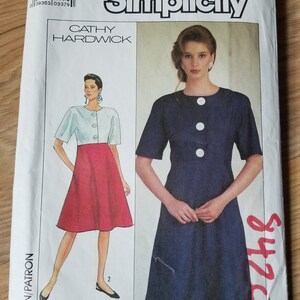 May include: Simplicity sewing pattern number 9420 for a dress with a white top and a red skirt, and a blue dress with buttons. The pattern is for sizes 6 and 8. The pattern is by Cathy Hardwick.
