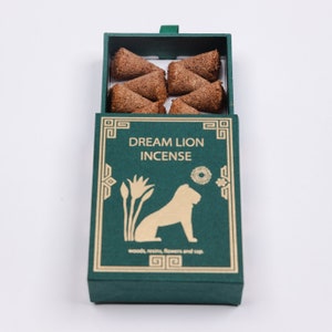 May include: A green box with gold lettering that reads "Dream Lion Incense" and a gold illustration of a lion. The box contains eight brown incense cones.