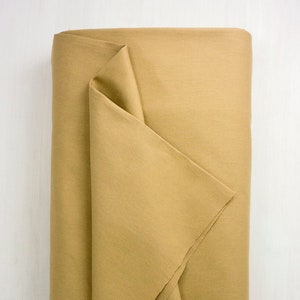 May include: A folded roll of beige cotton fabric. The fabric has a subtle texture and a slightly rough feel.