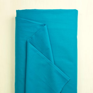 May include: A folded piece of turquoise blue fabric. The fabric is smooth and has a slight sheen.