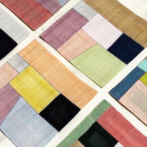 Op de afbeelding: Een set van zes kleurrijke vierkante stoffen met een patchwork-ontwerp. Elk vierkant is gemaakt van verschillende gekleurde stoffen die in een geometrisch patroon aan elkaar zijn genaaid. De vierkanten zijn in een kruispatroon gerangschikt.