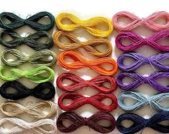 May include: A collection of 16 spools of colorful twine, each tied in a figure eight shape. The twine is made of natural fibers and comes in a variety of colors, including green, yellow, orange, red, purple, blue, and brown.