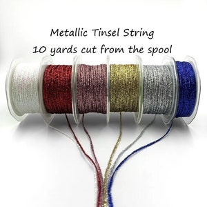 May include: Six spools of metallic tinsel string, each 10 yards long. The colors are white, red, pink, gold, silver, and blue.