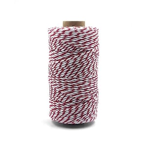 May include: A spool of red and white baker's twine. The twine is wound around a cardboard spool.
