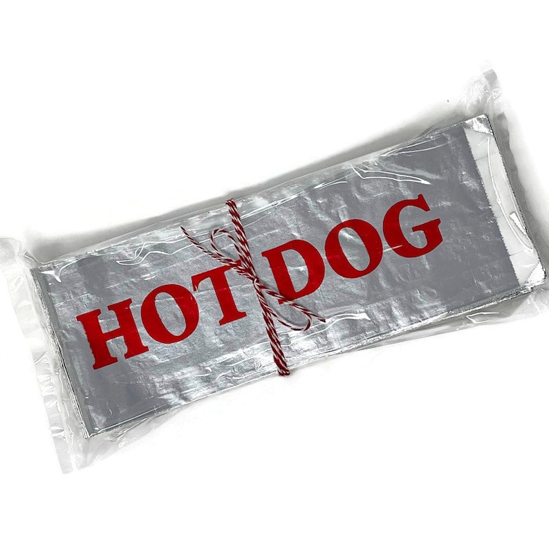 May include: A stack of silver foil hot dog wrappers with red text that reads "HOT DOG" tied together with red and white twine.