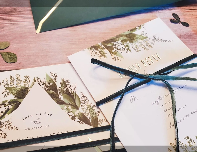 May include: A wedding invitation with a green and white floral design. The invitation is tied with a green velvet ribbon and includes a RSVP card with a list of dinner options.