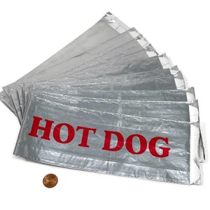 May include: A stack of ten silver foil hot dog wrappers with red lettering that says "HOT DOG".
