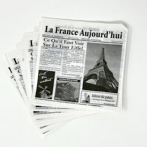 May include: A black and white newspaper with the headline "La France Aujourd'hui" and a photo of the Eiffel Tower. The text "Ce Qu'il Faut Voir Sur La Tour Eiffel" is also visible.