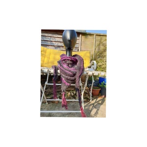 May include: A purple and black crocheted scarf with tassels. The scarf is draped over a mannequin head.