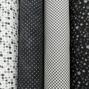 May include: Four rolls of fabric with different black and white patterns. The patterns include geometric shapes, polka dots, gingham, and stars.