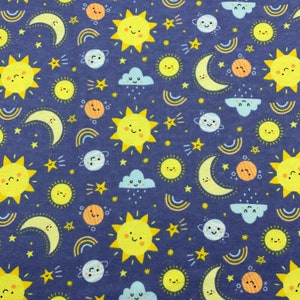 717 Flannel fabric denim blue background with smiling yellow suns half moons and stars rainbows blue clouds and planets sold by the yard.