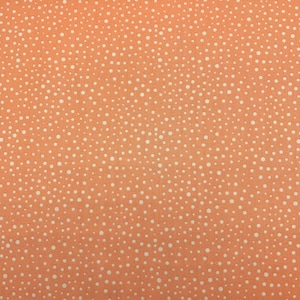 221 COTTON fabric light orange back ground with irregular white polka dots sold by the yard.