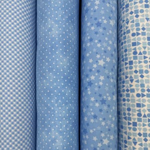May include: Four rolls of blue fabric with different patterns. The patterns include gingham, polka dots, stars, and geometric shapes.