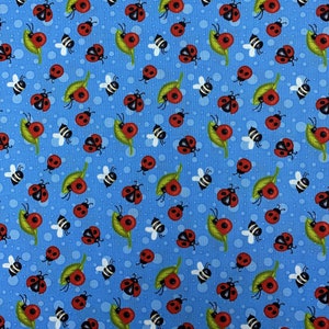 May include: A blue fabric with a repeating pattern of red ladybugs, green leaves, and white bees. The ladybugs are in various positions, some with their wings open and some with their wings closed. The leaves are green and have a simple shape. The bees are white and have black stripes.