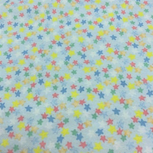 May include: A light blue fabric with a repeating pattern of small, multi-colored stars. The stars are in shades of yellow, pink, green, and blue.